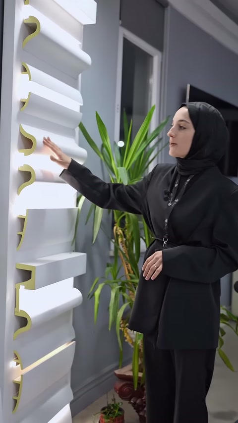 Sunucu, dikey sergideki kıvrımlı poliüretan profil kesitini eliyle tanıtıyor.