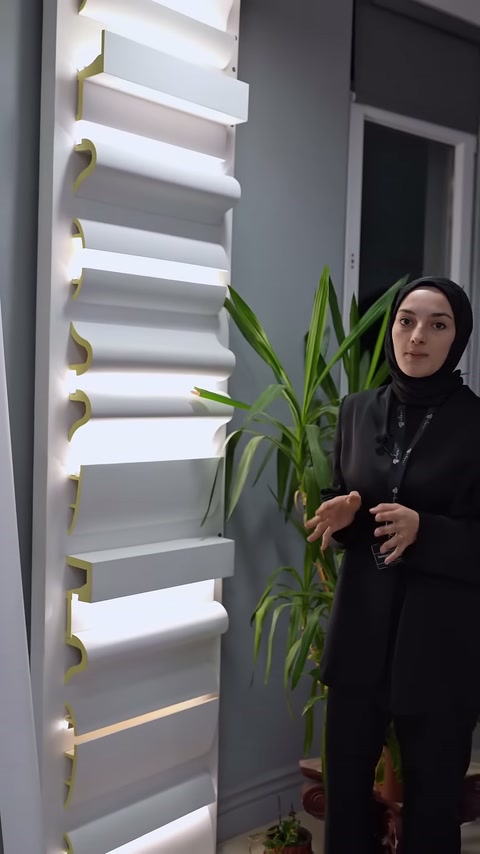 Sunucu, ışıklı profil panosu önünde ürün çeşitlerini açıklamayı sürdürüyor.