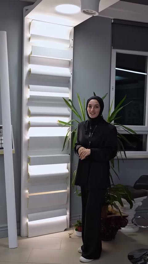 Sunucu, ışık veren dekoratif kartonpiyerlerin yanında ayakta duruyor.
