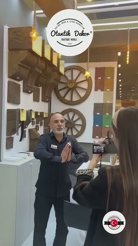 Sunum görevlisi duvardaki kiriş profilleri önünde ürünleri eliyle açıklıyor