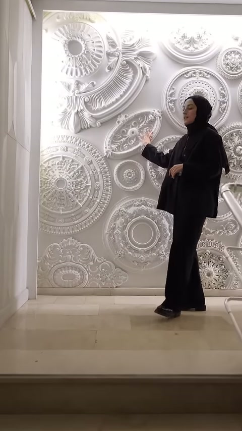 Sunucu, kabartmalı oval ve yuvarlak dekorların bulunduğu panoya yöneliyor