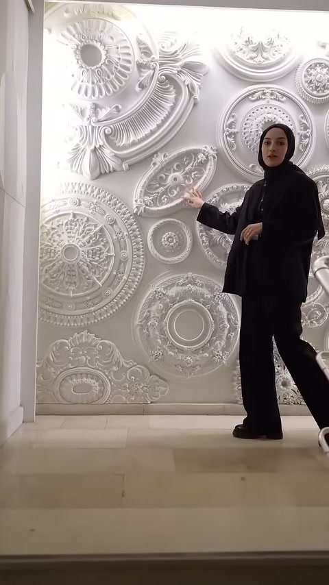 Showroomdaki sunucu, farklı motiflerle hazırlanmış tavan göbeklerini eliyle tanıtıyor