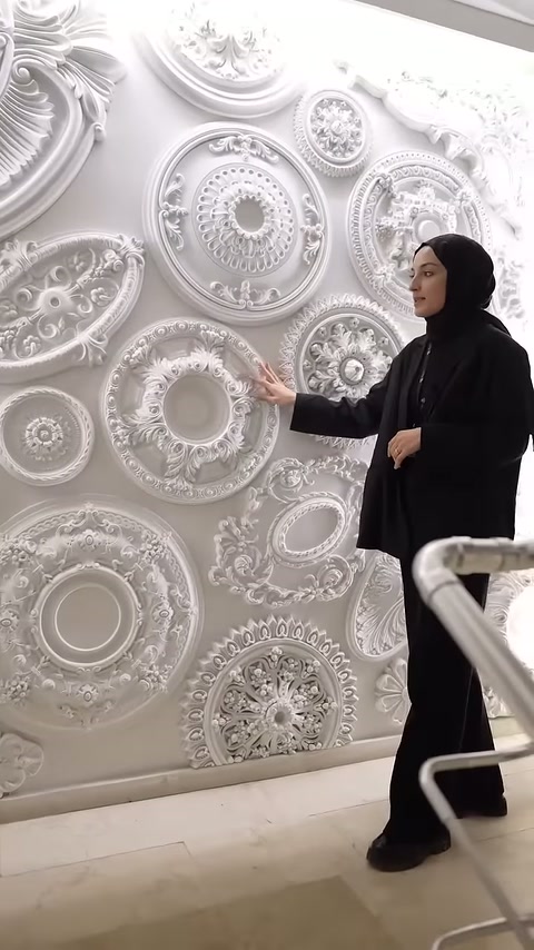 Sunucu, geniş çiçek çerçeveli göbek modelini açık avucuyla işaretliyor