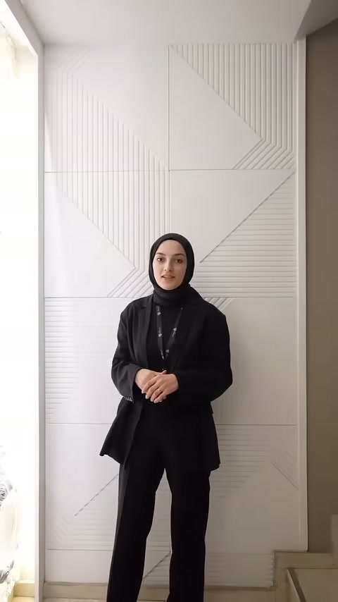 Sunucu, çizgisel geometrik desenli beyaz dekoratif duvar paneli önünde duruyor