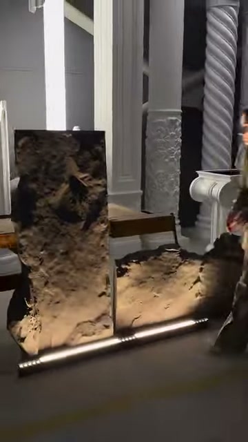 Dikey kaya panel, zemindeki ikinci parçayla birlikte ışık altında duruyor