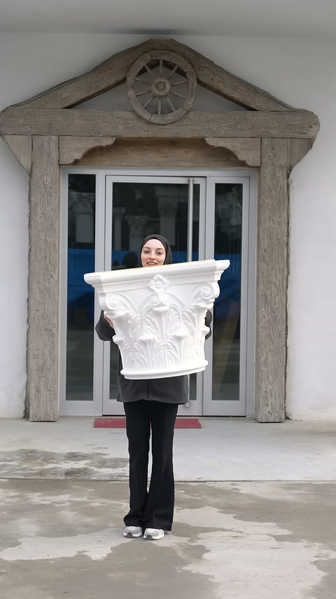 Beyaz yaprak motifli sütun başlığı cephe girişinde önden tutuluyor