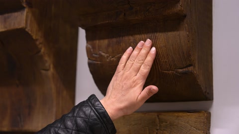 Ahşap görünümlü yüzeyin kabartılı dokusuna elle temas ediliyor