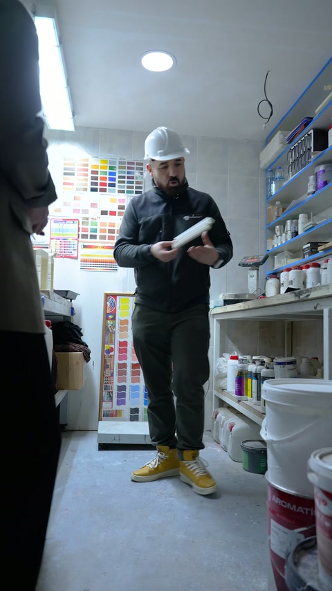 Görevli, beyaz kavisli poliüretan numuneyi laboratuvarda elinde inceliyor