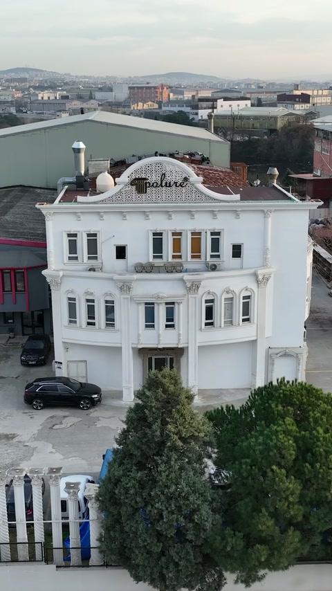 Klasik söve ve sütunlarla dekore edilmiş showroom binası havadan görülüyor.