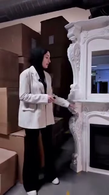 Sunucu beyaz şöminenin alt köşesindeki dekoratif ayrıntıları işaret ediyor