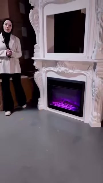 Sunucu beyaz şömine ünitesinin sol yanında izleyiciye konuşuyor