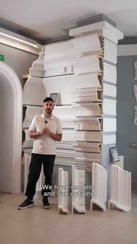 Sunucu showroomda dikey duran farklı genişlikteki söve modellerini açıklıyor.