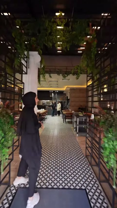Bitkilendirilmiş restoran girişinde dekoratif sütunlu iç mekâna geçiş görülüyor.