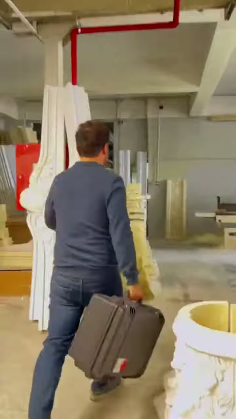 Üretim tesisinde görevli, tarama ekipmanıyla sütun modellerinin arasından ilerliyor.