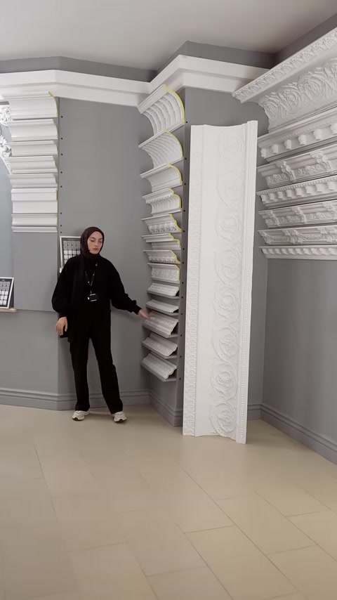 Sunucu, sergi alanındaki farklı kartonpiyer profillerini işaret ederek tanıtıyor.