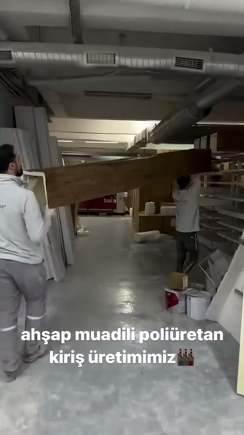 Çalışanlar kütük biçimli poliüretan kirişi yatay şekilde taşıyor.
