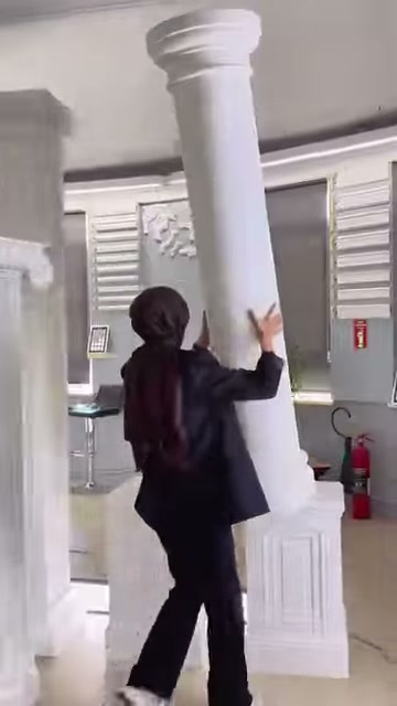 Tanıtıcı, beyaz sütunun yuvarlak gövdesindeki pürüzsüz yüzeyi eliyle gösteriyor.