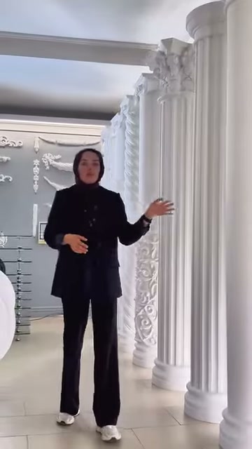Tanıtıcı, beyaz sütun koleksiyonu önünde modelleri eliyle işaret ediyor.