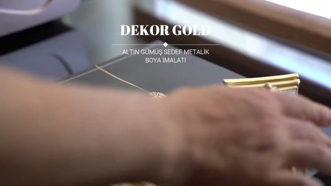 El, masa üzerindeki altın dekoratif süsleri düzenleme aşamasında konumlandırıyor.