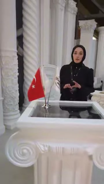 Sunucu, cam yüzeyli sehpa modülü önünde ürün sunumunu sürdürüyor