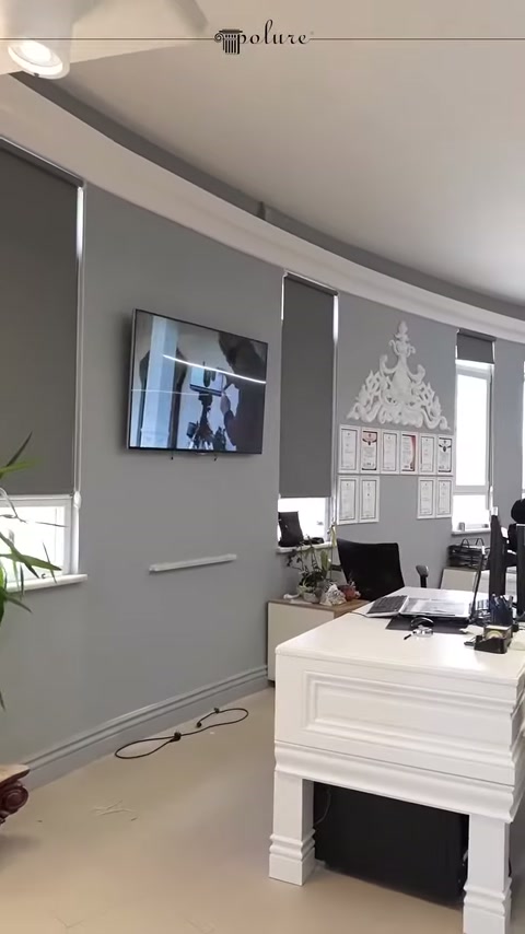 Gri showroom duvarında dekoratif çerçeveler ve çalışma masası bulunuyor
