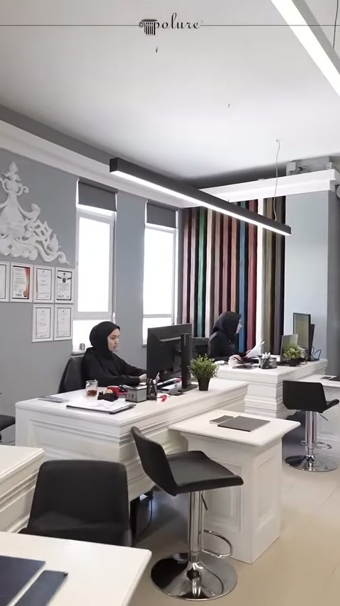 Bilgisayarlı çalışma masaları dekoratif gri duvarların önünde sıralanıyor