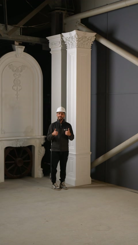 Sunucu atölyede Korint başlıklı sütun ve pilasterlerin önünde duruyor