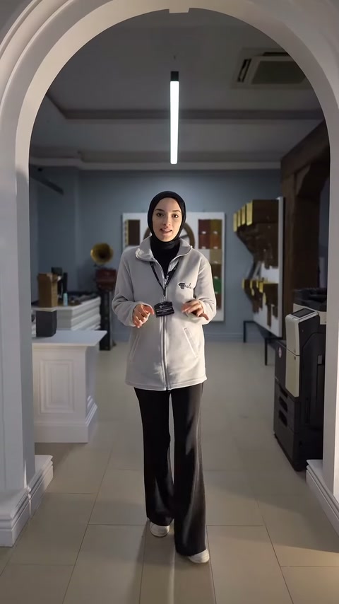 Kemerli iç mekân girişinde duran sunucu tanıtımını sürdürüyor