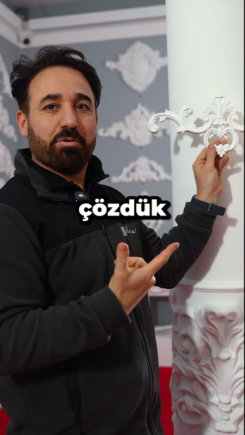 Usta, kıvrımlı süsleme elemanını sütun yanında işaret ederek tanıtıyor.